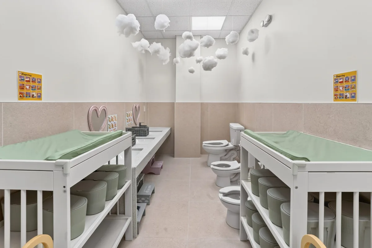 Bright changing room with two changing stations and toddler toilets