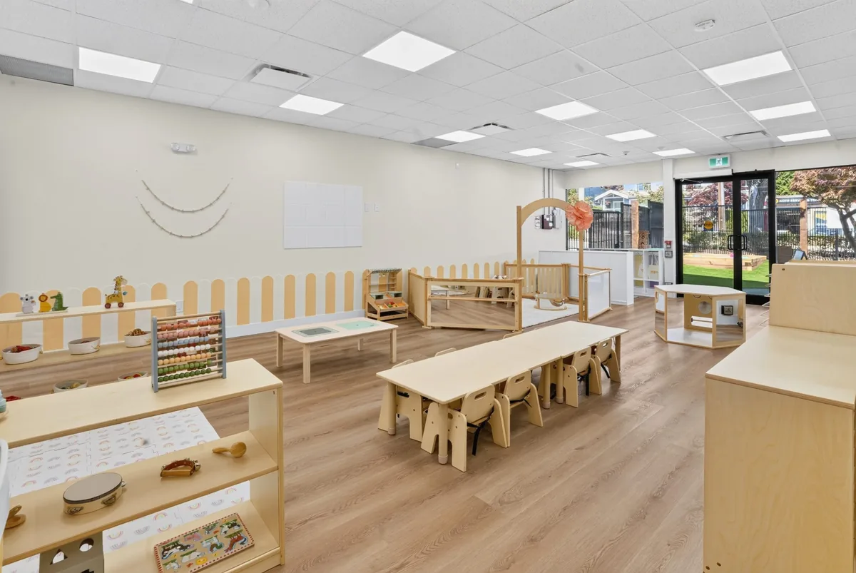 Sunlit MIM classroom with child-sized wooden tables and open shelving