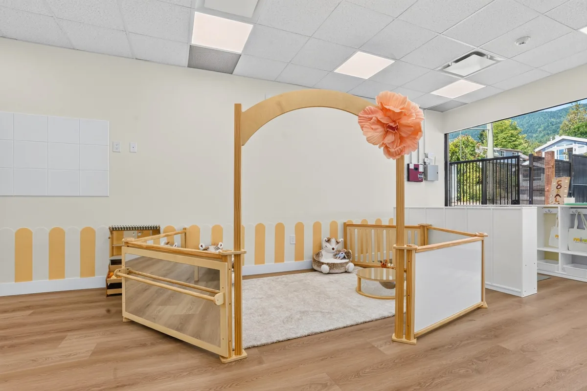 Soft infant play area framed by a wooden arch and low safety gate