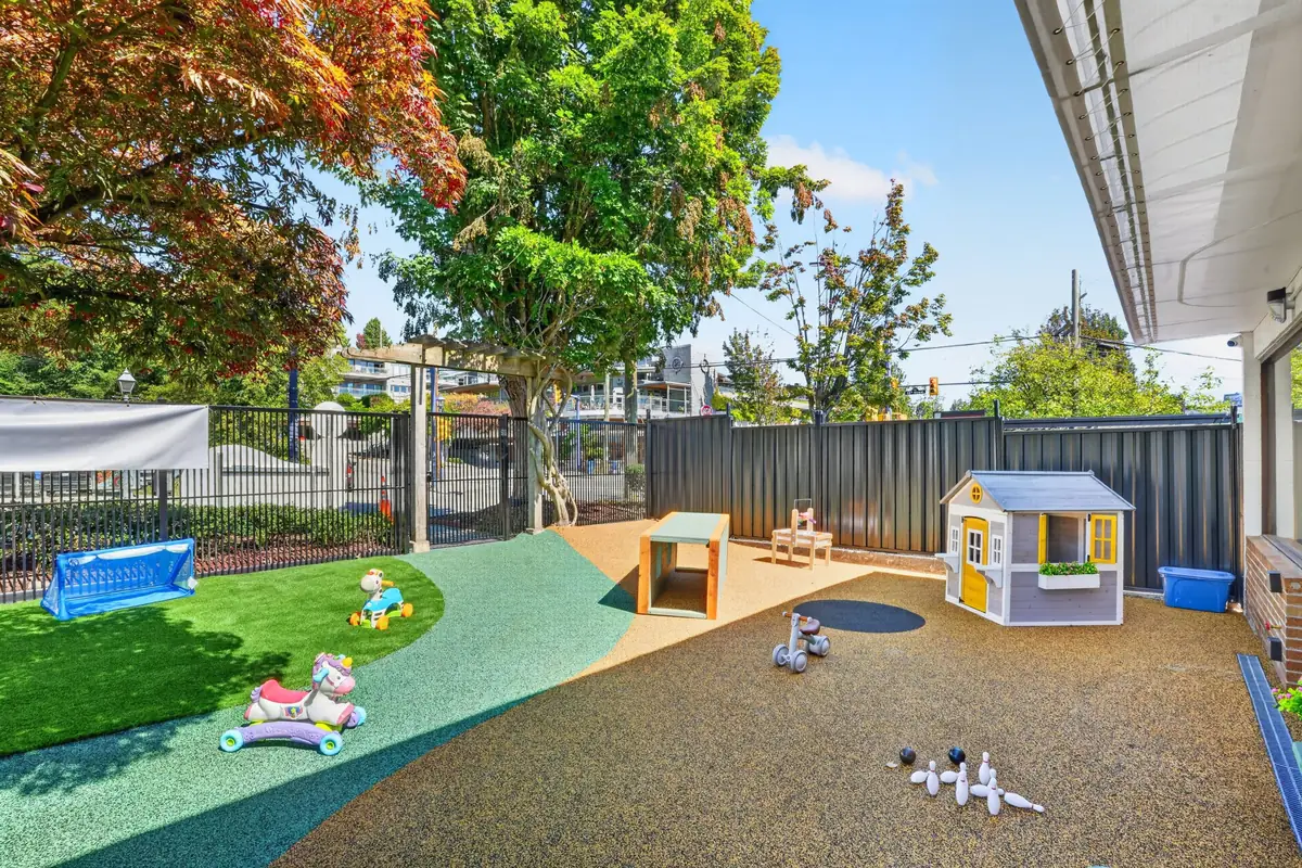 Wide view of the secure MIM outdoor yard with a playhouse