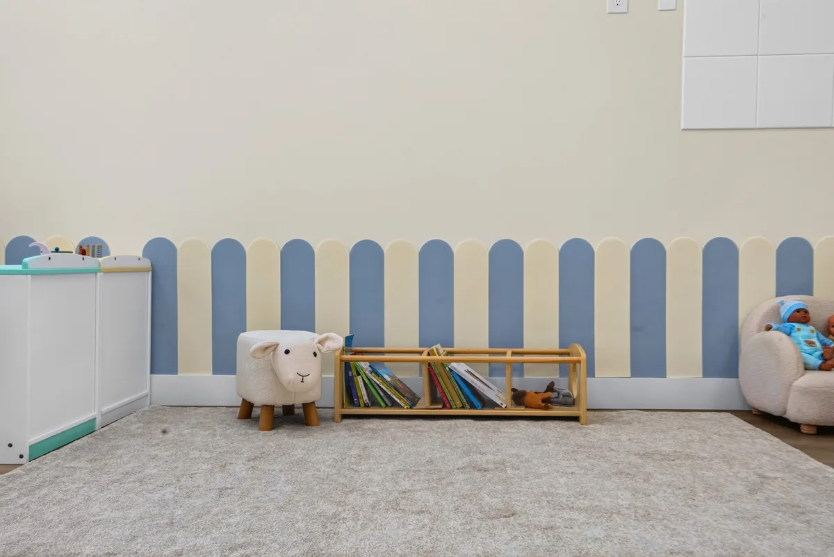 Quiet reading corner with a low book shelf, a sheep stool and an armchair