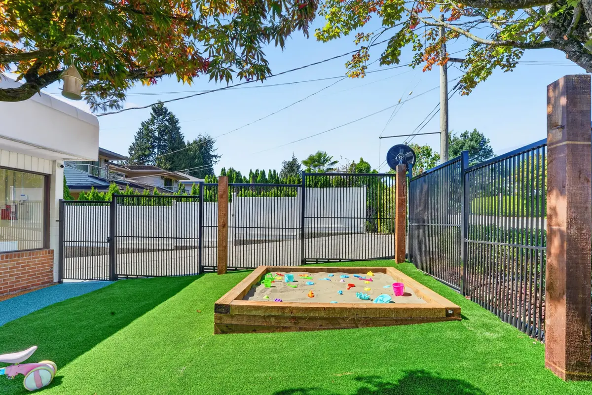 Wooden sandbox on green turf in the MIM play yard